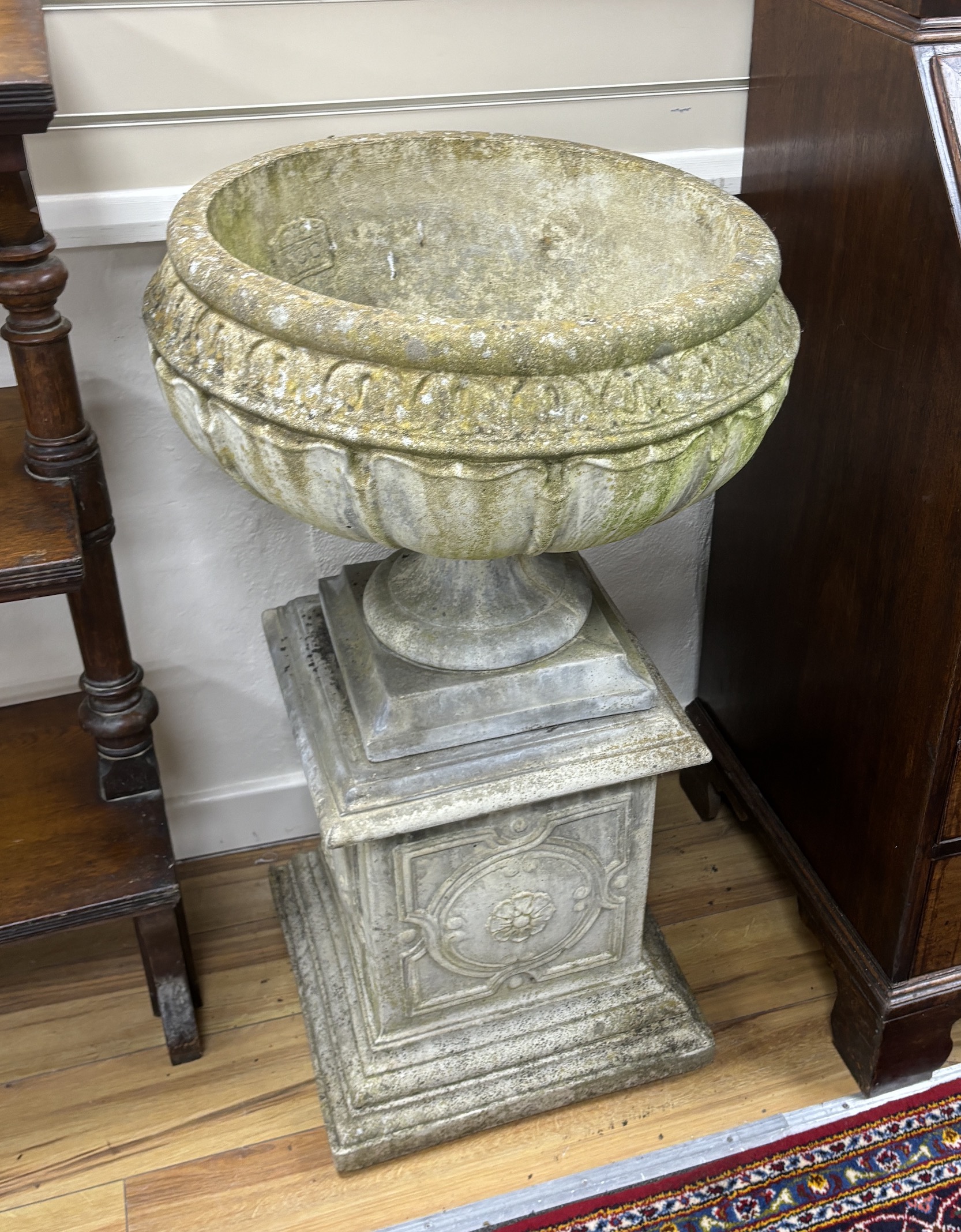 A set of three circular reconstituted stone garden urns on square plinths, diameter 54cm, height 95cm